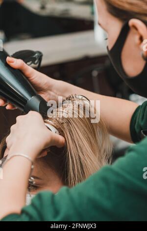 Séchage des cheveux avec un sèche-cheveux et une brosse ronde, coiffage. Nouveau Banque D'Images