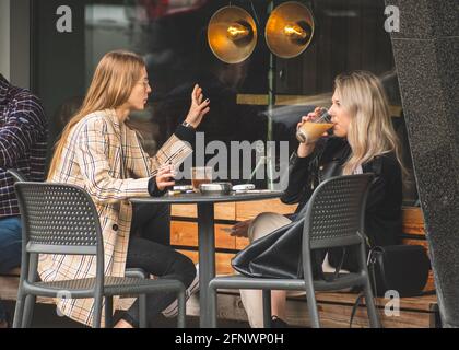 Deux belles filles sans masque, assis et buvant du café dans un bar, un café ou un restaurant en plein air après des restrictions de quarantaine Banque D'Images