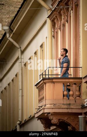 Homme ou garçon fumant de la cigarette à l'extérieur sur le balcon, à la verticale Banque D'Images