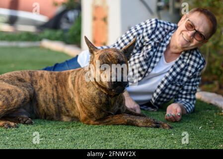 Femme mature avec un chien à l'arrière-cour regardant le portrait de l'appareil photo. Mise au point sélective sur le chien. Banque D'Images