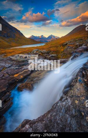 Cascade, lumière du soir, et alpenglow dans le paysage montagneux à Vengedalen, Rauma kommune, Møre og Romsdal, Norvège, Scandinavie. Banque D'Images