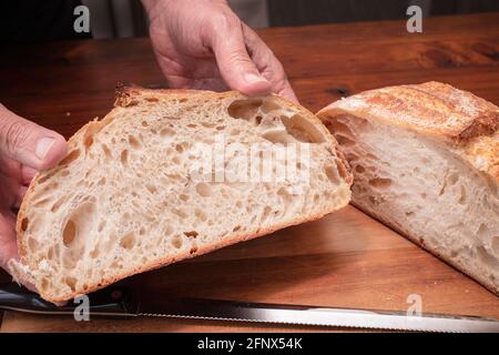 Pain de levain fait maison coupé en tranches sur une planche à découper par le chef, après avoir été cuit au four Banque D'Images