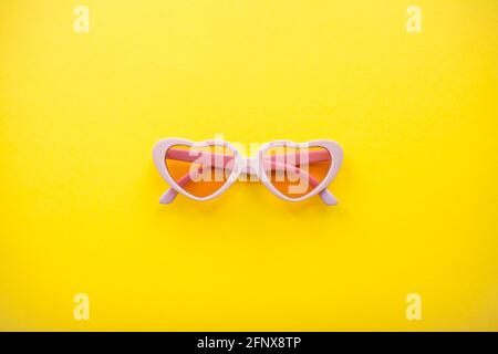 Mise en page. Verres roses sous forme de coeurs sur fond jaune vif. Été Banque D'Images