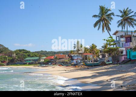 Plage déserte avec bateaux, maisons et palmiers à Dutch Bay, Trincomalee, Sri Lanka Banque D'Images