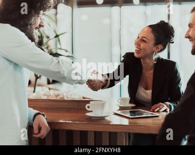 Un groupe de professionnels en pause-café utilisent des ordinateurs portables, des tablettes et des smartphones tout en discutant de nouveaux projets d'entreprise. Banque D'Images