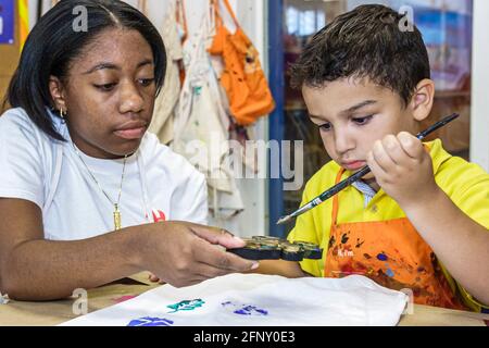 Miami Florida, Children's Museum t-shirt atelier de décoration, hispanique garçon enfant enfant peinture Noir fille femelle, adolescent adolescent adolescent adolescent étudiant bénévole Banque D'Images