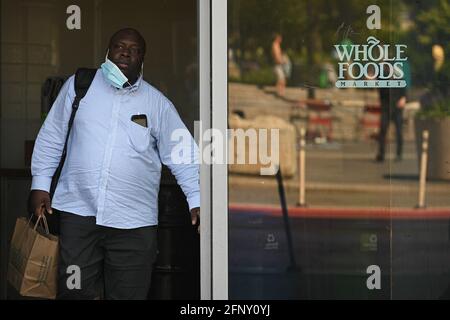 New York, États-Unis. 19 mai 2021. Un homme avec un masque à moitié usé quitte Whole Foods Market à Union Square alors que la ville de New York rouvre officiellement, soulevant le mandat de masque pour les personnes qui sont entièrement vaccinés, et 100% de capacité pour les bureaux, les restaurants, les gymnases et les musées, New York, NY, 19 mai 2021. Whole Foods a indiqué que les personnes vaccinées peuvent magasiner sans masques. Les personnes qui ne sont pas encore entièrement vaccinées seront invitées à suivre le système d'honneur et à garder leur masque et à maintenir leurs distances sociales. (Photo par Anthony Behar/Sipa USA) crédit: SIPA USA/Alay Live News Banque D'Images