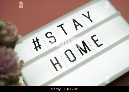 Stay Home mot dans la boîte à lumière sur fond rose Banque D'Images