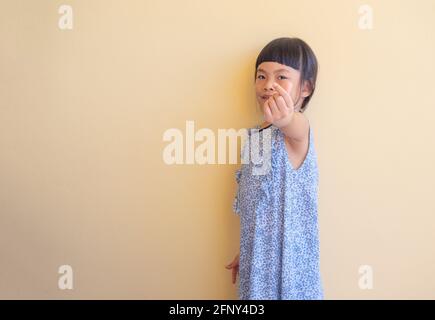 Petite fille drôle montrant le mini symbole de coeur en utilisant ses doigts. Petite fille en robe bleue en vacances. Banque D'Images