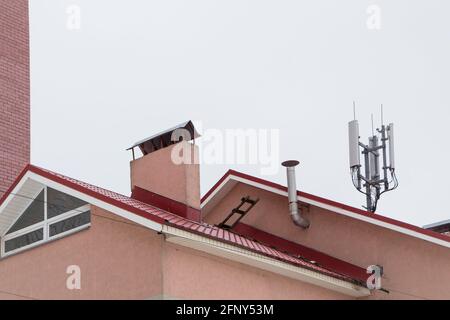 Antenne de télécommunication à côté de la cheminée et du bâtiment résidentiel. Communications cellulaires et téléphoniques. Cheminée contre le ciel gris. Le concept de la vie moderne dans la ville. Banque D'Images