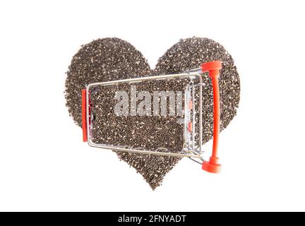 Petit panier plein de graines de chia debout sur un symbole de coeur fait de la salvia hispanica graines Banque D'Images