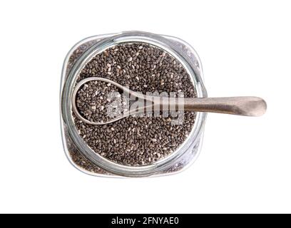 Vue de dessus d'un pot en verre plein de graines de chia avec une cuillère en acier sur le dessus isolée sur blanc Banque D'Images