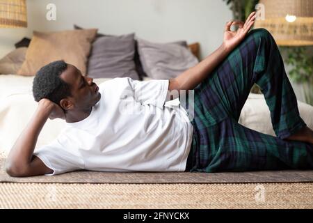 Homme africain de yoga faisant antasana pose s'entraîner à la maison Banque D'Images