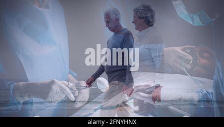 Couple senior se réveillant sur la plage contre l'équipe de chirurgiens port de masques faciaux en cours d'opération Banque D'Images