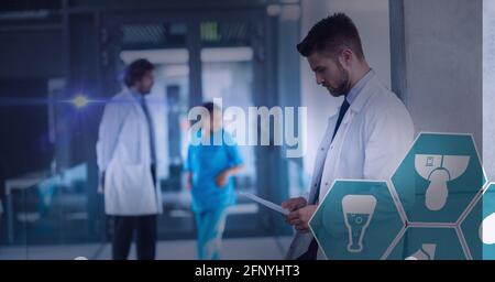 Spot de lumière et de multiples icônes médicales contre le médecin masculin utilisation d'une tablette numérique à l'hôpital Banque D'Images