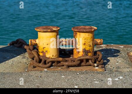Un double bollard d'amarrage de bitt avec une chaîne lourde autour d'elle. Banque D'Images