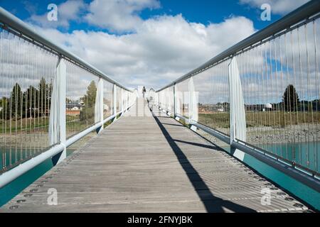 Un homme qui marche sur le pont du lac Tekapo, avec une rampe de pont qui jette une longue ombre, South Island Banque D'Images