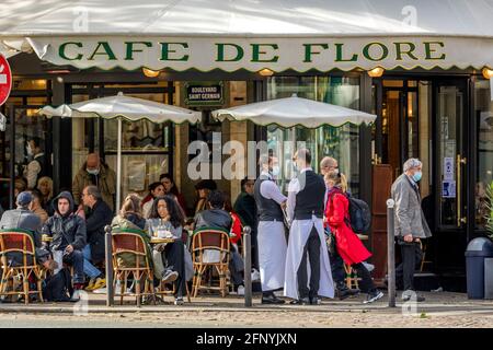 Paris, France - 19 mai 2021 : jour après l'enfermement dû au covid-19 dans un célèbre café parisien. 2 serveurs portent des masques chirurgicaux Banque D'Images