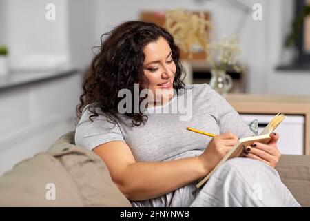 jeune femme heureuse avec journal sur le canapé à la maison Banque D'Images