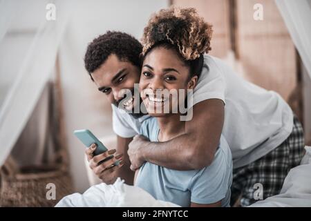Jeune mari et femme à la peau noire en pyjama avec smartphone Banque D'Images
