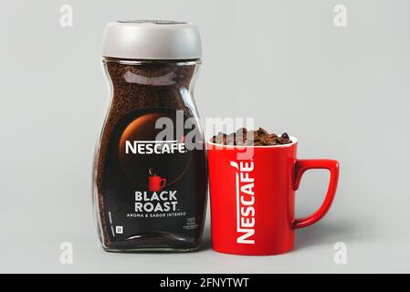 Pot de Nescafé Black Roast et tasse rouge de Nescafé avec grains de café sur fond gris Banque D'Images