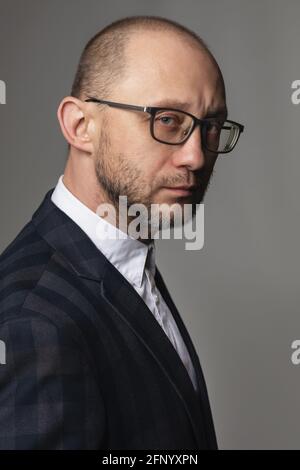 Portrait d'un homme avec un look pensif dans un costume et des lunettes. Banque D'Images