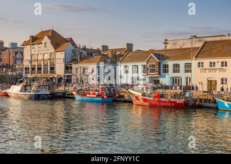 Vue sur les bateaux dans le vieux port et les maisons de quai au coucher du soleil, Weymouth, Dorset, Angleterre, Royaume-Uni, Europe Banque D'Images