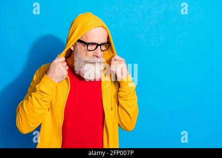 Photo de l'homme mature concentré dans les verres regarder copyspace porter une capuche de survêtement isolée sur fond bleu Banque D'Images