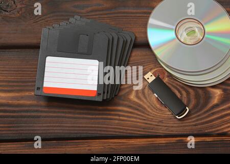 Disquettes, lecteur flash USB et disques sur fond de bois Banque D'Images