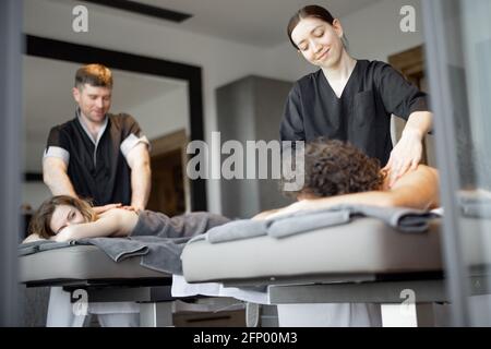 Beau couple allongé dans un salon de spa appréciant un massage profond du dos et de détente. Le bien-être et les loisirs pour les soins de santé ensemble. Concentrez-vous sur l'homme. Lumière naturelle. Banque D'Images