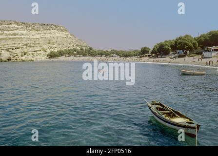 Image d'archivage. Vue vers les grottes de Matala. La plage non fréquentée de Matala, dans le sud de la Crète, avec un bateau amarré à l'avant-plan. Célèbre pour son artific Banque D'Images