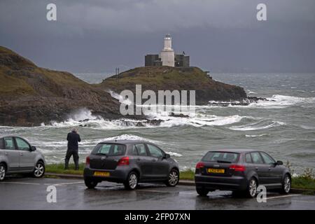 Swansea, Royaume-Uni. 20 mai 2021. Un homme brave les gales pour prendre une photo pendant que les vagues se brisent dans les rochers de la baie de Bracelet, devant le phare de Mumbles près de Swansea, cet après-midi, pendant la tempête force de vents forts. Credit: Phil Rees/Alamy Live News Banque D'Images