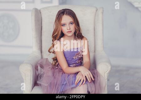 portrait de la belle petite fille caucasienne portant la robe, assise sur une chaise Banque D'Images