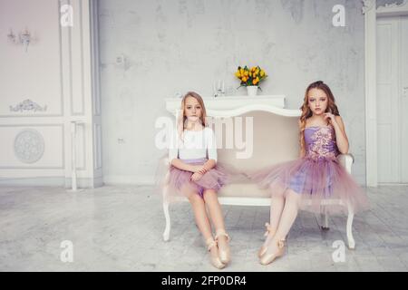 Petite fille assise dans un studio de ballet avec espace de copie. Deux petites ballerines mignonnes assises sur l'école de danse classique Banque D'Images