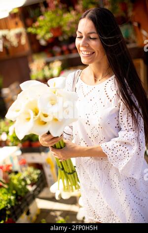 Jolie jeune femme achetant des fleurs au marché aux fleurs Banque D'Images