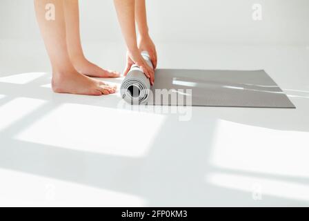 Vue latérale de Crop anonyme mince femme tapis roulant pour pratique de yoga en studio blanc Banque D'Images