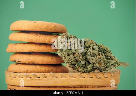 Bonbons à l'huile CBD. Bourgeons de marijuana sur fond vert. Fleurs de cannabis et biscuits au chocolat en gros plan. Banque D'Images