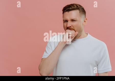 Jeune homme ennuyé bâillant et couvrant la bouche ouverte avec le poing Banque D'Images