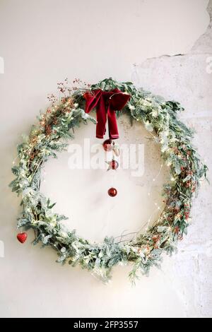 Couronne de Noël élégante ornée d'un noeud rouge et de boules suspendues mur de béton en baque pendant les fêtes Banque D'Images