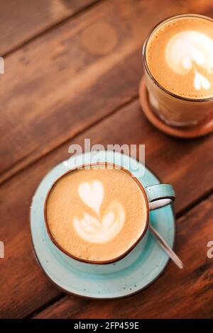Du dessus des tasses en céramique sur les soucoupes fraîchement brassées latte avec les cœurs sur la mousse Banque D'Images