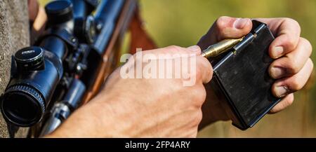 L'homme charge un fusil de chasse. Chasseur masculin prêt à chasser. Gros plan. Munitions avec un pistolet, cartouches. Chasseur. Période de chasse. L'homme est allumé Banque D'Images