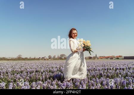 portrait d'une femme debout sur des champs de jacinthe et tenant des tulipes Banque D'Images