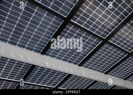 Panneaux d'énergie solaire installés sur des poutres en acier pour couvrir un parking, vu de dessous. Énergie durable et ombre en même temps Banque D'Images