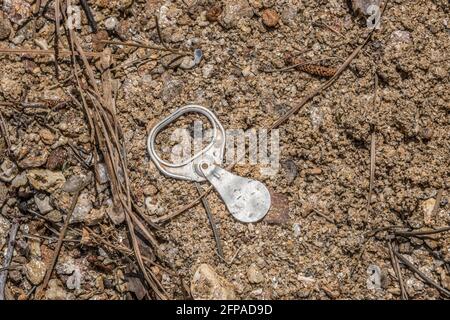 Ancien tirette vintage d'une canette de soda ou de bière s'étendre à l'envers sur la plage au lac polluant l'environnement lors d'une journée ensoleillée au printemps Banque D'Images