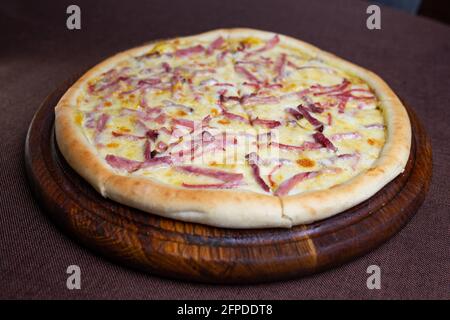 pizza fraîche avec saucisse et fromage sur un support en bois. Banque D'Images