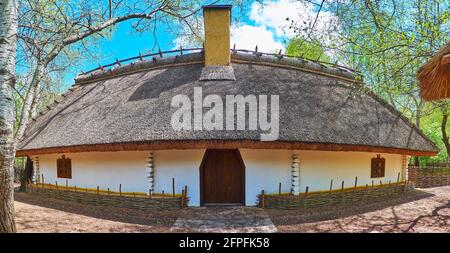 Panorama de la maison traditionnelle ukrainienne de hata blanchie à la chaux avec toit taillé, entouré d'une clôture en osier, située dans le vieux domaine de Blacksmith, Mamajeva Banque D'Images