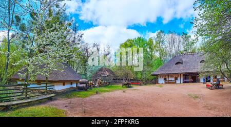 Panorama de la cour au shynok (restaurant et bar ukrainien traditionnel) avec maisons de hata, tables et bancs, fûts et une grange en arrière-plan, Ma Banque D'Images