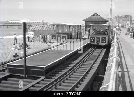 1962, historique, vue de la plate-forme ferroviaire et du train sur le chemin de fer étroit, le Volk's Electric Railway (VER ou VR) qui longe le front de mer de Brighton, Angleterre, Royaume-Uni. Construit pour la première fois par l'inventeur et ingénieur électrique de Briitsh Magnus Volk en 1883, il est resté en service depuis. Banque D'Images