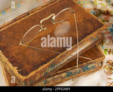 Lunettes anciennes à bord d'or sur des livres en cuir. Banque D'Images