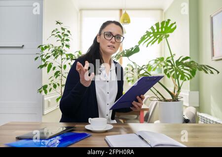 Femme d'affaires regardant la caméra parler, tenant des documents dans les mains Banque D'Images